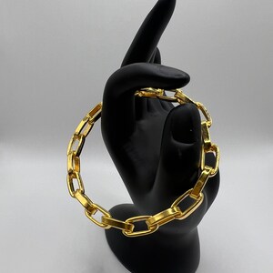 Könnte beinhalten: Ein goldenes Kettenarmband mit dickem, klobigem Gliederdesign.