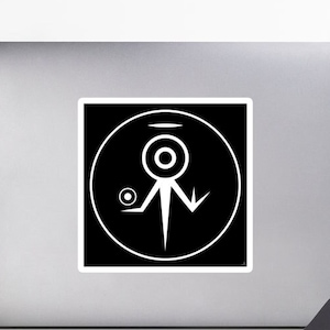 May include: A square white sticker with a black border features a white abstract symbol inside a circle. The symbol includes a central eye-like shape, a smaller circle, and a stylized figure with downward-pointing lines. The sticker is on a laptop.