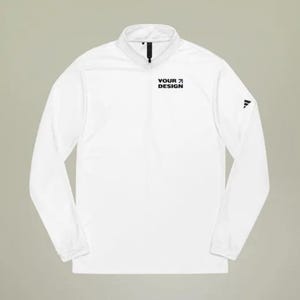 May include: White long-sleeved shirt with a zipped collar and a black logo that says "YOUR DESIGN" on the front. The shirt has a black logo on the right sleeve.