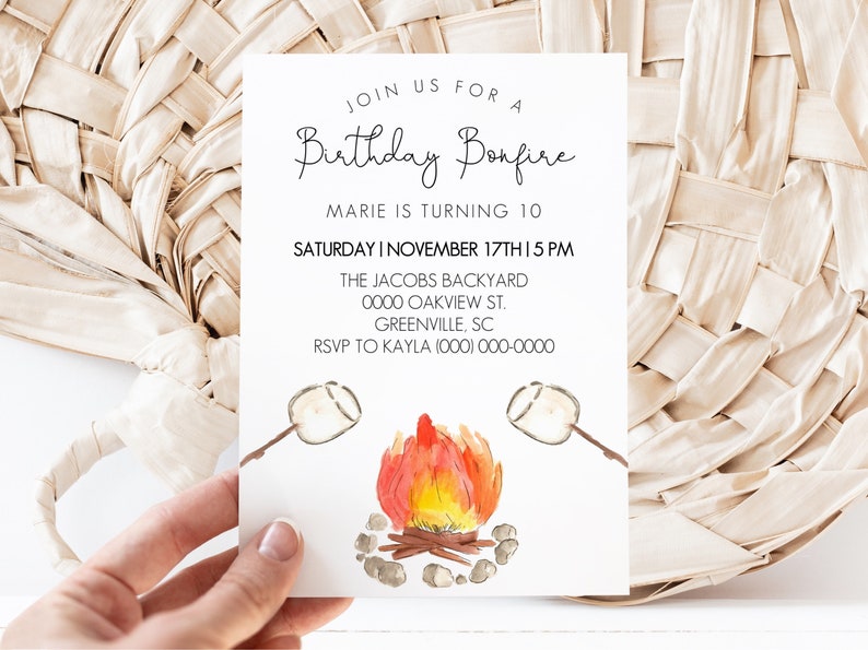 May include: A white invitation card with black text for a birthday bonfire party. The text reads "Join us for a Birthday Bonfire, Marie is turning 10, Saturday | November 17th | 5 PM, The Jacobs Backyard, 0000 Oakview St., Greenville, SC, RSVP to Kayla (000) 000-0000". The card features a watercolor illustration of a campfire with two marshmallows on sticks.