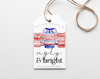 May include: A white gift tag with a watercolor illustration of three festive sweaters. The tag reads "May your sweaters be ugly & bright" with the family name at the bottom. A brown twine is attached to the tag.