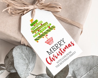 Może przedstawiać: Biała etykieta prezentowa z akwarelowym wzorem choinki. Drzewko jest zielone z czerwonymi i pomarańczowymi akcentami. Na etykiecie napis "MERRY Christmas" w kolorze czerwonym i czarnym, z spersonalizowaną wiadomością poniżej.