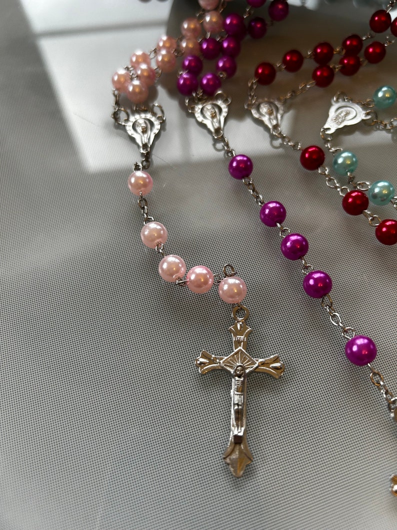 May include: A silver rosary with a crucifix and beads in pink, purple, red, and blue.