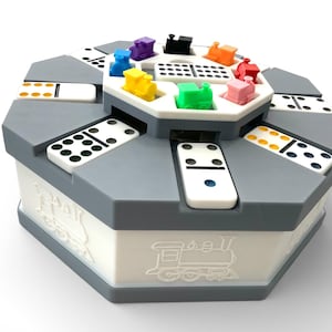May include: A gray and white domino game set with colorful train-shaped game pieces. The set includes white dominoes with black and yellow dots. The box has a train graphic on the side.