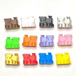 May include: A collection of twelve miniature train figurines in various colors. The trains are brown, white, black, silver, green, orange, purple, pink, gold, red, blue, and yellow. Each train has a detailed design.