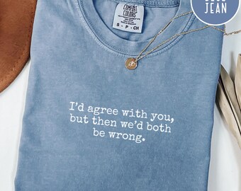 May include: A blue jean Comfort Colors t-shirt with the text "I'd agree with you, but then we'd both be wrong." A gold necklace with a pendant rests on the shirt. The shirt is folded neatly.