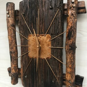 Puede incluir: Un reloj de madera r&uacute;stico con una esfera de cobre y agujas doradas. El reloj est&aacute; hecho de madera recuperada y tiene un aspecto &uacute;nico y artesanal.