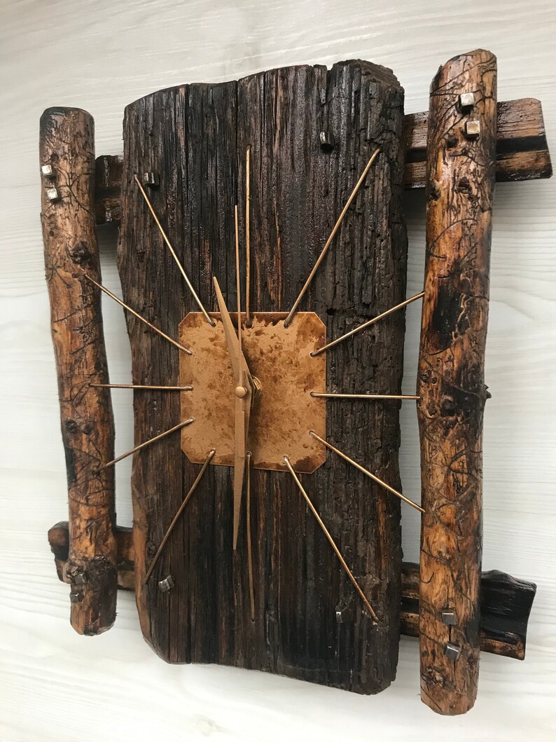 Puede incluir: Un reloj de madera r&uacute;stico con una esfera de cobre y agujas doradas. El reloj est&aacute; hecho de madera recuperada y tiene un aspecto &uacute;nico y artesanal.