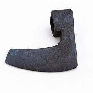 Könnte beinhalten: Ein dunkelgrauer, antiker Axtkopf mit gebogener Klinge und rechteckigem Auge für den Stiel. Das Metall weist Gebrauchsspuren und Alter auf, mit einer leicht rauen Textur. Der Axtkopf ist vor weißem Hintergrund isoliert.