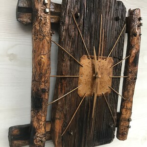 Puede incluir: Un reloj de madera r&uacute;stico con una esfera dorada y agujas de metal. El reloj est&aacute; hecho de madera recuperada y tiene un aspecto &uacute;nico y artesanal.