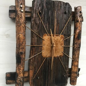 Puede incluir: Un reloj de madera r&uacute;stico con una esfera marr&oacute;n y agujas doradas. El reloj est&aacute; hecho de madera recuperada y tiene un aspecto &uacute;nico y artesanal.