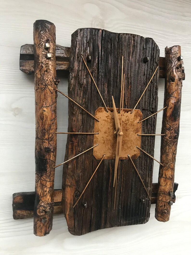 Puede incluir: Un reloj de madera r&uacute;stico con una esfera marr&oacute;n y agujas doradas. El reloj est&aacute; hecho de madera recuperada y tiene un aspecto &uacute;nico y artesanal.
