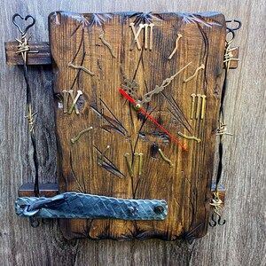 Puede incluir: Reloj de pared rústico de madera con números romanos y detalles decorativos de metal. La esfera del reloj es de madera oscura con números y manecillas de color latón. El reloj tiene un segundero rojo y mide unos 30 cm cuadrados.