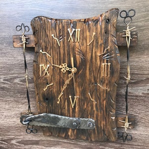 Può includere: Un orologio in legno rustico con numeri romani, circondato da filo spinato e accenti metallici. Il quadrante dell'orologio è marrone scuro con una finitura invecchiata.