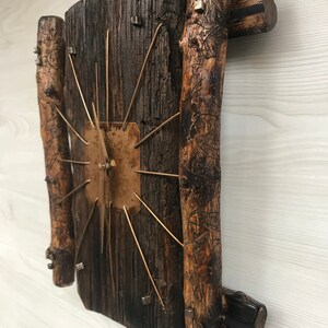 Puede incluir: Un reloj de madera r&uacute;stico con una esfera de cobre y agujas de metal. El reloj est&aacute; hecho de madera reciclada y tiene un aspecto &uacute;nico y artesanal.