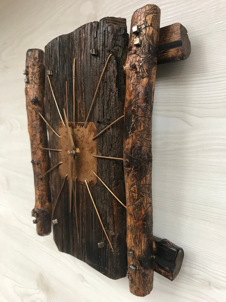 Puede incluir: Un reloj de madera r&uacute;stico con una esfera de cobre y agujas de metal. El reloj est&aacute; hecho de madera reciclada y tiene un aspecto &uacute;nico y artesanal.