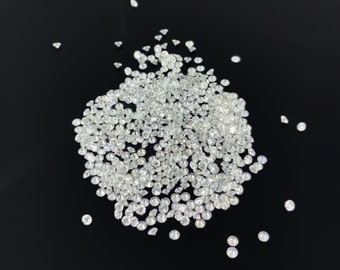 May include: A large pile of small, clear, round diamonds on a black background.