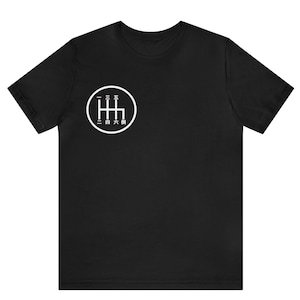 May include: Black t-shirt with a white circle graphic of a 6-speed manual transmission gear shift pattern. The numbers 1 through 6 are written in Japanese characters around the circle.