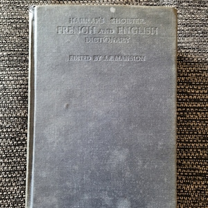 May include: A blue hardcover book with the title "Harrap's Shorter French and English Dictionary" and the text "Edited by J.E. Mansion".