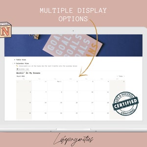 May include: A laptop screen displaying a calendar with the text "Workin' On My Dreams" and a "Life & Success Certified Coaching" stamp. The calendar is for March 2022 and April 2022. The laptop is on a pink background.