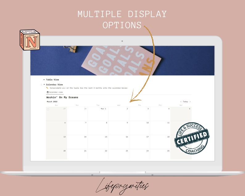 May include: A laptop screen displaying a calendar with the text "Workin' On My Dreams" and a "Life & Success Certified Coaching" stamp. The calendar is for March 2022 and April 2022. The laptop is on a pink background.