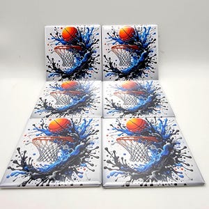 May include: Six square ceramic coasters featuring a basketball going through a net, with a splash of blue and black water. The basketball is orange, the net is white, and the background is white.
