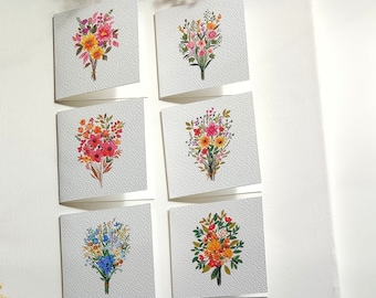 Könnte beinhalten: Satz von sechs leeren Grußkarten mit Aquarell-Illustrationen von bunten Blumensträußen. Jede Karte hat einen weißen Hintergrund und eine strukturierte Papieroberfläche.