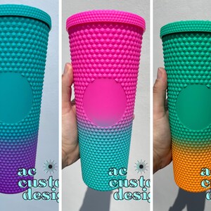 Puede incluir: Tres vasos de doble pared que cambian de color con una superficie texturizada y con hoyuelos. Los vasos son de color turquesa, rosa y verde con un efecto degradado. Los vasos son todos del mismo tamaño y forma.
