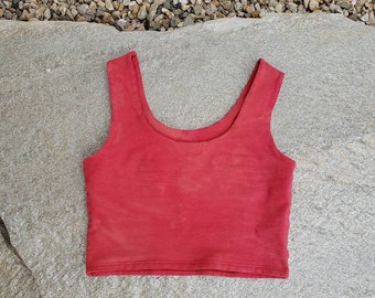 May include: A red sleeveless crop top with a scoop neck.
