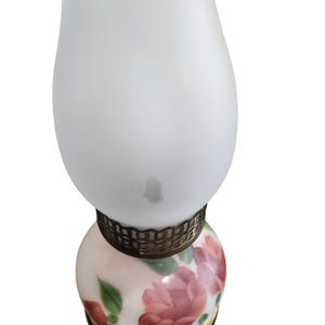 May include: A white frosted glass lamp with a floral design on the bottom. The lamp has a gold metal band around the middle.
