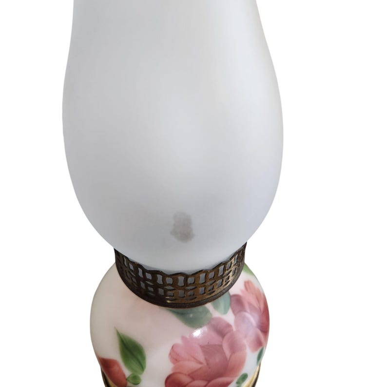 May include: A white frosted glass lamp with a floral design on the bottom. The lamp has a gold metal band around the middle.