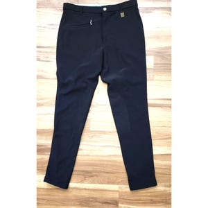May include: Black riding pants with a button and zipper closure. The pants have a small pocket on the front and a patch on the inner leg. The pants are made of a smooth, dark fabric.