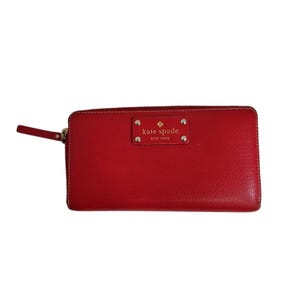 Cartera Kate Spade New York de piel roja con cremallera y placa dorada con el logotipo