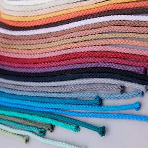 May include: A collection of colorful cotton cords arranged in a fan shape. The cords are various shades of red, pink, purple, blue, green, and brown.