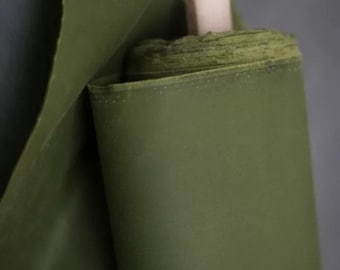 May include: A roll of dark green fabric is folded over itself. The fabric is tightly rolled and has a smooth texture.