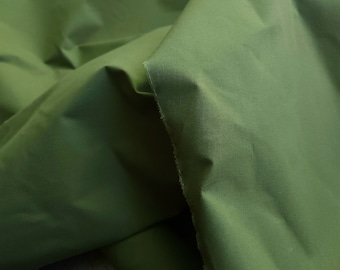 May include: A close-up of a folded piece of green fabric. The fabric has a smooth, slightly shiny surface.