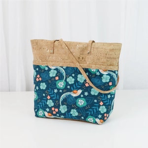 May include: A blue and brown tote bag with a cork top and a floral pattern featuring birds and leaves.
