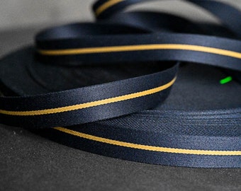 May include: A roll of navy blue ribbon with a single thin gold stripe running down the center.