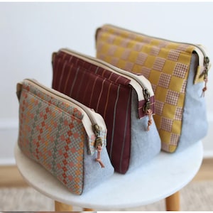 May include: Three different sized zippered pouches with various patterned fabric. The pouches are lined with a light gray fabric and have a cream colored zipper.