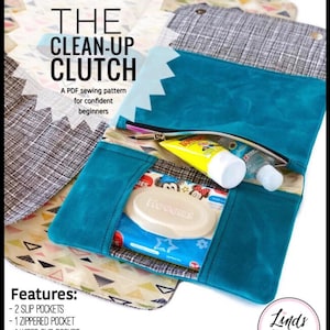 May include: A teal blue zippered clutch with a removable changing pad and pockets for wipes, diapers, and other baby essentials. The clutch measures 10 inches wide by 7 inches high by 1 inch deep. The text "THE CLEAN-UP CLUTCH" is displayed in white on a blue background. The text "Features" is displayed in black on a pink background. The text "Linds Handmade Authorized Retailer" is displayed in white on a black circle.