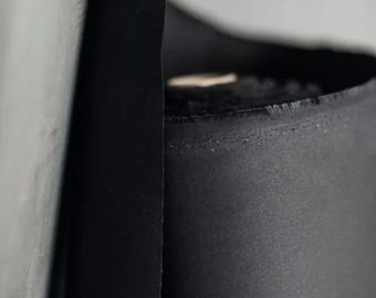 May include: Close-up of a black fabric roll, showing the edge of the fabric and the seam along the side.