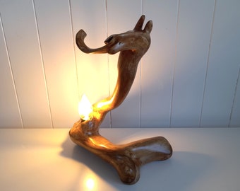 Puede incluir: Una lámpara de madera con forma de animal estilizado con una bombilla que ilumina el espacio a su alrededor.