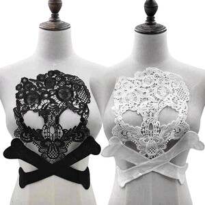 Puede incluir: Dos aplicaciones de encaje en forma de calavera, una negra y otra blanca, con huesos cruzados. Las aplicaciones se muestran en maniquíes.