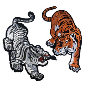 Può includere: Due toppe ricamate da stirare con due tigri che si fronteggiano. La tigre a sinistra è bianca e la tigre a destra è arancione.