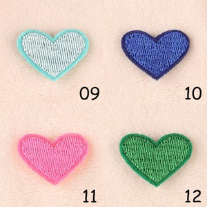 May include: Four embroidered heart-shaped patches in different colors: light blue, dark blue, pink, and green. The patches are arranged in a grid pattern on a white background. The numbers 09, 10, 11, and 12 are printed below each patch.