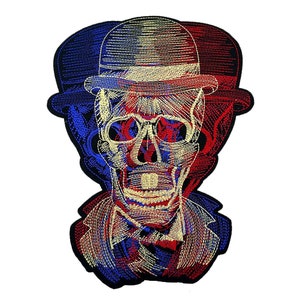 Peut inclure: Patch brodée thermocollante représentant un crâne portant un chapeau melon rouge, blanc et bleu. Le crâne est souligné de fil doré et présente un design détaillé.
