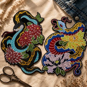 May include: Two embroidered patches featuring detailed snake designs with floral accents. One snake is black with blue and yellow details, the other is yellow with red and blue. Both have intricate stitching and vibrant colors.