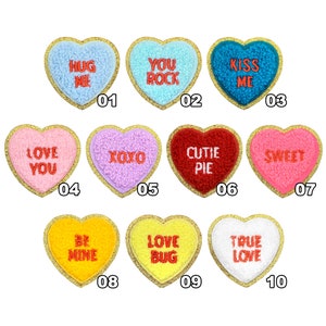 May include: Ten heart-shaped felt patches with gold trim and embroidered messages. The messages include "Hug Me", "You Rock", "Kiss Me", "Love You", "XOXO", "Cutie Pie", "Sweet", "Be Mine", "Love Bug", and "True Love".