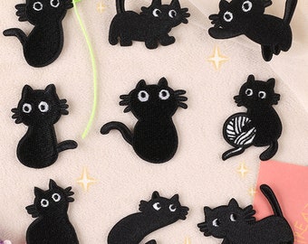 May include: Set of ten black embroidered iron-on patches featuring cartoon cats in various poses.