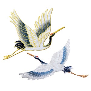 May include: Two embroidered iron-on patches of white cranes with black and blue accents. The crane on the left has gold accents and a long, thin beak. The crane on the right has a shorter, thicker beak.